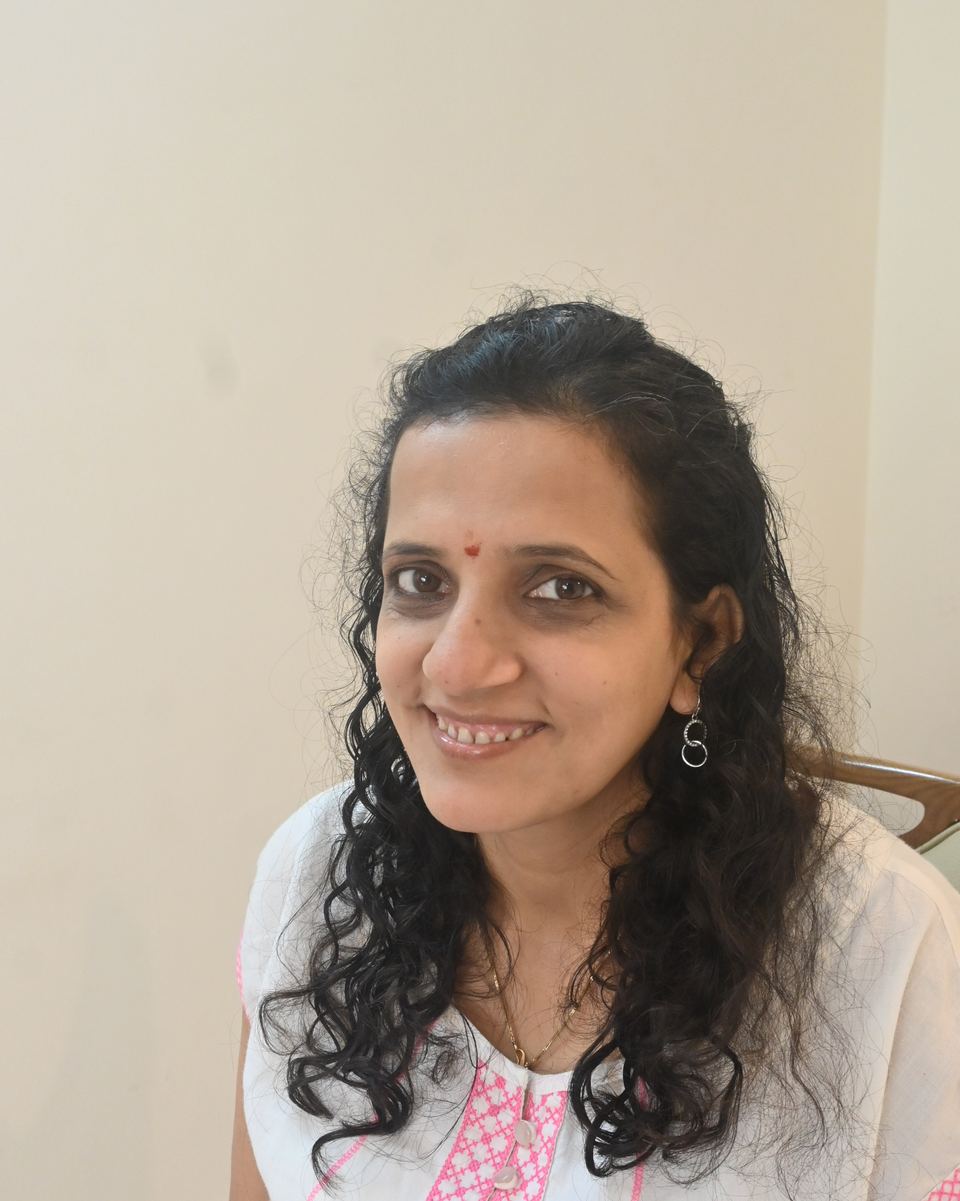 Portrait of Ritu, smiling, seated in a white kurta
